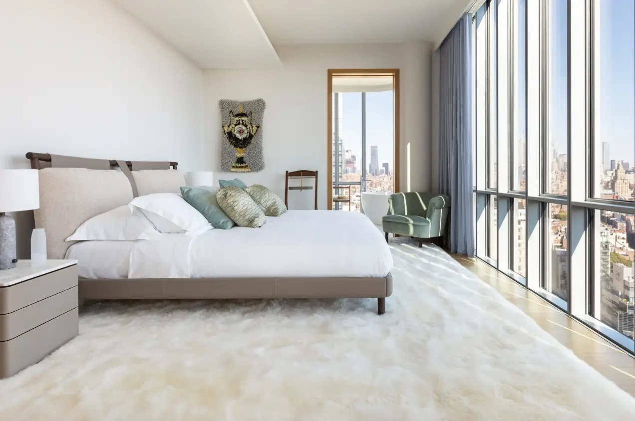 A bright bedroom with crisp white bedding and floor-to-ceiling city views